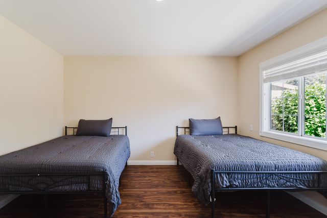 Bedroom with wood-look flooring and a large window facing the yard