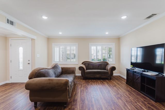 Living room with wood-look flooring, recessed lighting, plantation shutters and the front entry door