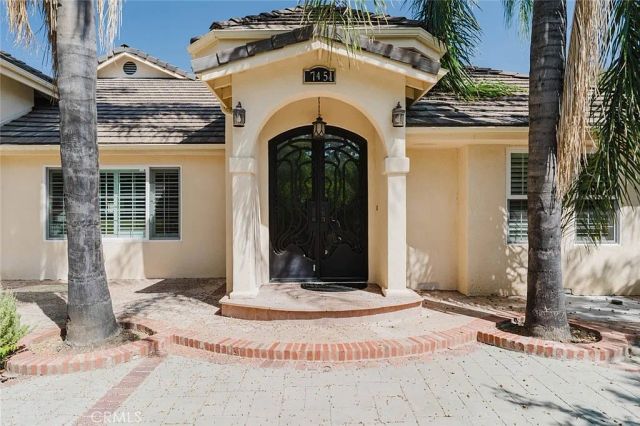 Arched front porch with decorative double doors and palm trees at 17451 Osborne Street