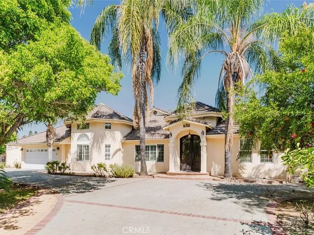 Front exterior of 17451 Osborne Street with palm trees, an arched entry and driveway