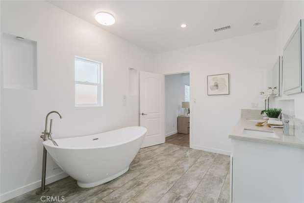 Primary bathroom with a freestanding soaking tub, floor-mounted filler and tile flooring