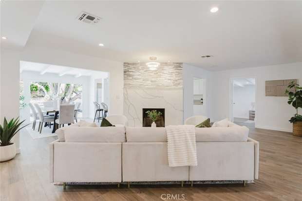 Open living room with a white sectional sofa, stone fireplace surround and sliding doors to the backyard patio