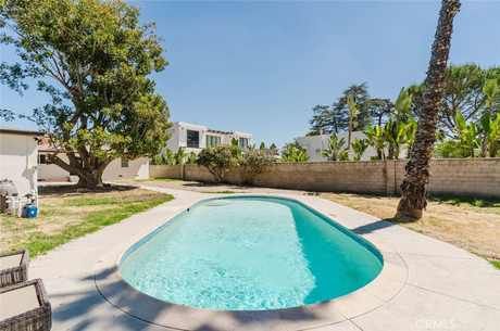 Backyard in-ground pool with a concrete deck, mature trees and block wall fencing