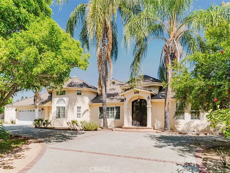 Front exterior of 17451 Osborne Street with palm trees, an arched entry and driveway